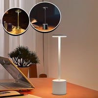 Lampe de table rechargeable blanche, noire et dorée posée près d’un ordinateur et d’un livre