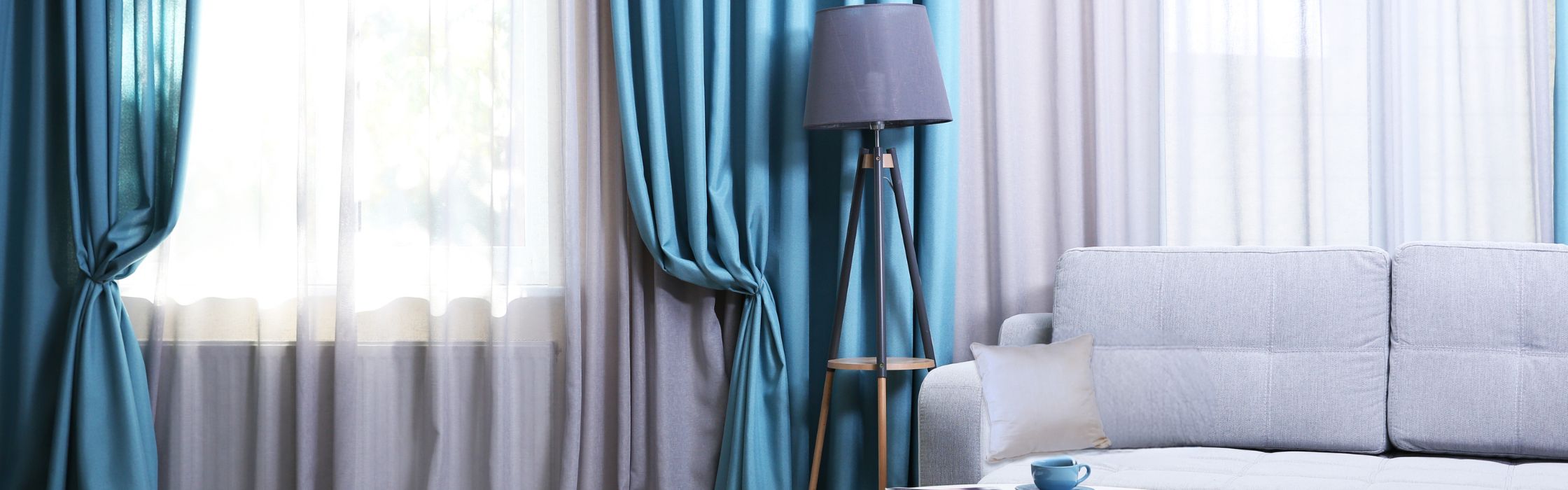 Des rideaux bleus et blanc avec canapé gris