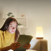 Jeune fille qui utilise la lampe de chevet sans fil comme lampe de lecture