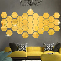 Lot de Vingt Quatre Miroirs Adhésifs Hexagonaux en Acrylique sur un mur gris avec un canapé et des coussins