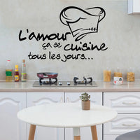 Stickers Cuisine Imperméable avec Citation en Plastique collé sur le mur d'une cuisine avec une plaque de cuisson et des placards en dessous une table devant et des bocaux à droite