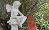 Statue de féé, en pierre blanche dans une jardin.