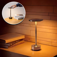 Lampe de table sans fil posée à côté des livres et  projetant une lumière douce  