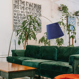 Abat Jour Chambre Décoratif en Velours dans une pièce avec un canapé vert et des plantes sur fond blanc