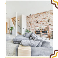 Un salon avec un canapé gris et un mur décoré en brique