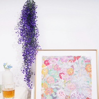 Fausse Plante Tombante Violette de Style Feuilles de Vigne sur fond blanc avec un tableau et un verre