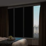 Film Occultant Total pour Fenêtre et Protection solaire installé sur des vitres avec des rideaux marron et un lit devant 