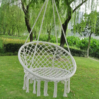 Hamac Sur Pied Rond de Style Chaise en Corde de Coton suspendu en extérieur sur fond d'herbe et d'arbres