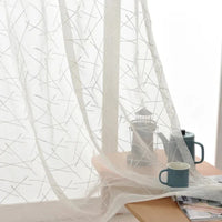 Rideau Transparent en Tulle avec Formes Géométriques Brodées sur une table avec une tasse dessus sur fond blanc